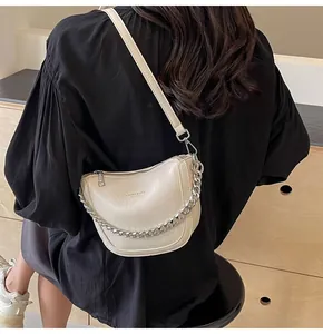 Model wearing a chic beige crescent bag with a metallic chain and leather strap