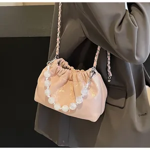 Rosa plissierte Beuteltasche mit großen Perlenhenkel und Kettenriemen am Modell gezeigt