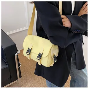 Detail shot of pale yellow nylon messenger bag featuring adjustable black plastic buckles