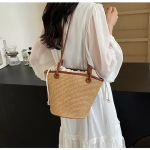 Detail of woven straw shoulder bag featuring brown leather straps and drawstring liner