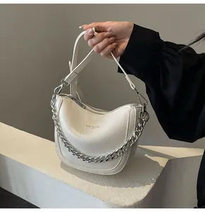 Detail of white half-moon hobo bag with textured finish and silver chain strap