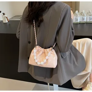 Detailansicht der rosa Falten-Eimertasche mit weißem Perlengriff und Metallkettenriemen