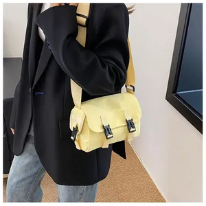 Detail shot of bright yellow messenger bag with black buckle closures on a stylish model