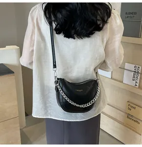 Detailed view of black textured hobo bag with silver chain and gold logo on the front
