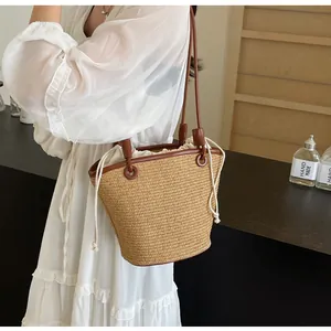 Detail of hand-woven straw bucket bag with brown leather handles and drawstring lining