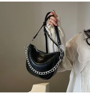 Close-up of black crescent hobo bag featuring glossy wrinkled texture and silver chain