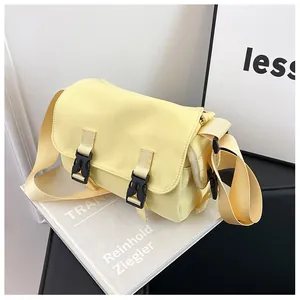 Detail view of the pale yellow canvas messenger bag featuring dual black buckle closures