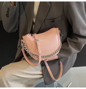 Detail of pink PU leather saddle bag with silver chain strap worn with a brown blazer