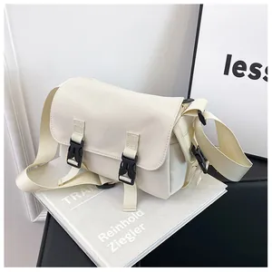 Detail of off-white canvas messenger bag with black buckles on a minimalist background