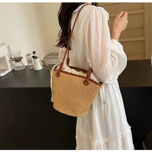 Detail of woven straw bucket bag with brown leather straps and drawstring inner liner