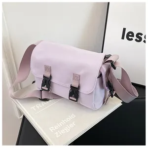 Detail of light purple canvas messenger bag with dual black buckle closures and adjustable strap