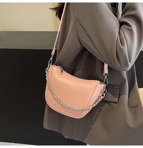 Detail of pink pleated crescent bag with chunky silver chain on model in dark blazer