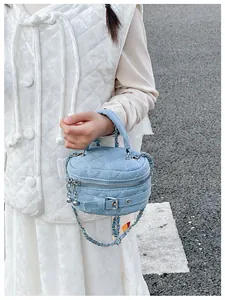 Close-up of light blue denim box bag with quilted rhombus texture and silver chain