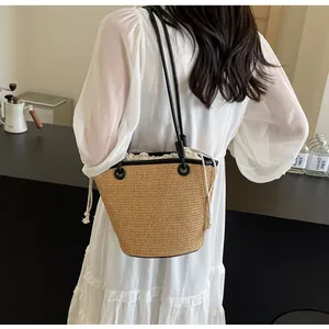 Close-up of woven straw bucket bag with black leather straps and drawstring liner
