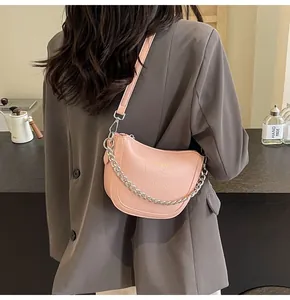 Close-up of light pink textured leather hobo bag with silver chain and gold lettering