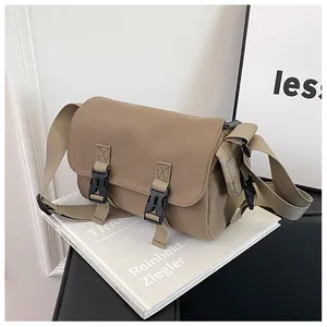 Detail of tan messenger bag with double black buckle closures and woven nylon strap
