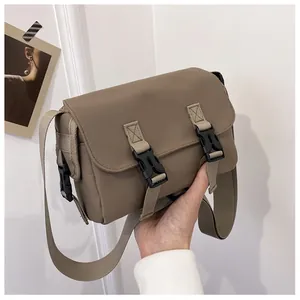 Detail of khaki messenger bag with dual buckle closures and adjustable nylon strap