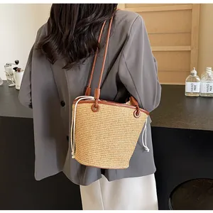 Close-up of woven straw bucket bag with brown leather trim and cotton drawstring lining