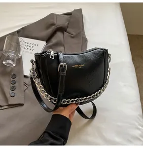 Detail of black crescent crossbody bag with silver chain and textured PU leather