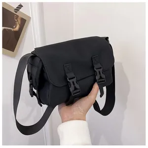 Close-up of black canvas messenger bag with double buckles and adjustable wide strap