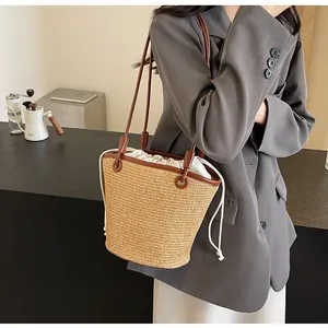 Detail of woven straw bucket bag with brown leather trim and drawstring closure