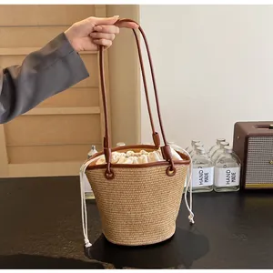 Detail of woven straw bucket bag with brown leather strap and drawstring closure