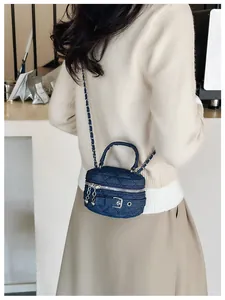 Detail of blue denim quilted mini vanity case with silver chain strap and metal ball charm