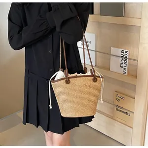 Detail of woven straw tote with brown leather strap and drawstring canvas lining bag