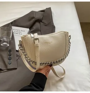 Detail of off-white dumpling crossbody bag featuring pleated leather and silver chain