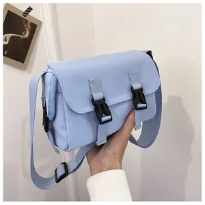 Close-up of light blue messenger bag with black plastic buckles and canvas texture