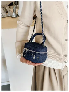 Detail of quilted denim mini round bag with silver chain strap and top handle