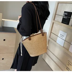 Detail of woven straw shoulder bag with leather straps and drawstring fabric lining