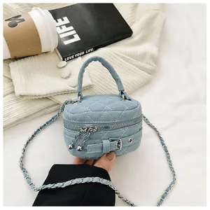 Macro shot of blue denim quilted round bag with white stitching and silver belt buckle