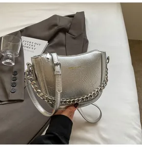 Detail of silver pleated crescent bag with metallic texture and chunky chain strap