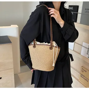Detail of woven straw tote bag featuring leather trim and cotton drawstring inner pouch