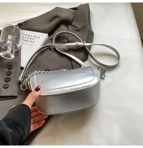 Close-up of silver saddle bag with wrinkled metallic texture and metal chain detail