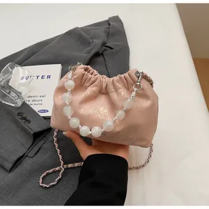 Detail der rosa gefalteten Beuteltasche mit weißem Perlenmgriff und silberner Kette