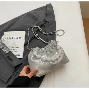 Details der silbernen Beuteltasche mit weißem Perlengriff und eleganter Metallkette