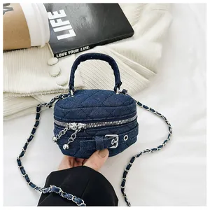 Detailed macro view of denim quilted mini bag with silver chain strap and metal ball zippers