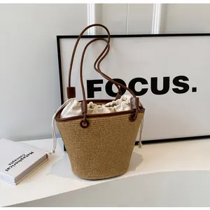 Detail of woven straw bucket bag with brown leather trim and canvas drawstring liner