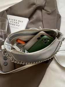 Silver wrinkled crossbody bag with chunky metal chain shown with daily essentials