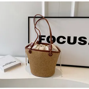 Detail of woven straw bucket bag with brown leather handles and a white drawstring lining
