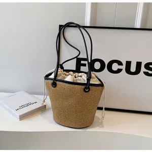Detail of hand-woven straw bucket bag with black leather trim and drawstring canvas liner