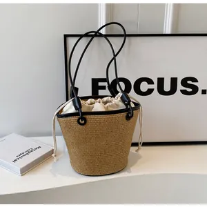 Detail of woven straw bucket bag with black leather trim and drawstring canvas closure