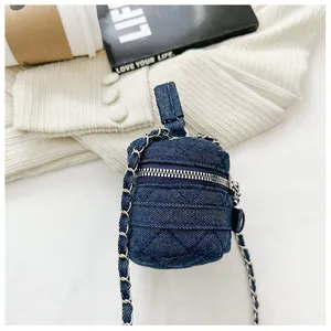 Detail of blue denim quilted mini bag with silver chain strap on a white knit background
