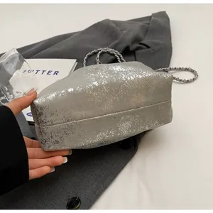 Detail der silbernen Eimertasche aus strukturiertem Leder mit Metallic-Riss-Effekt-Kette