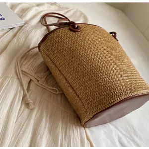 Close-up of woven bucket bag featuring brown leather trim and drawstring closure