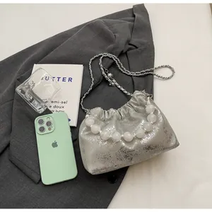 Detail der silbernen Metallic-Beuteltasche mit Marmorperlengriff und Kettenriemen