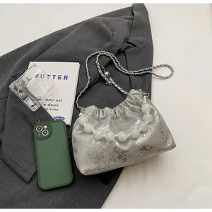 Details der silbernen Metallic-Samttasche mit Perlengriff und Metallkette