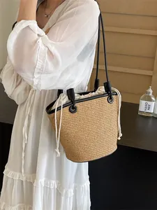 Minimalist woven straw bucket bag with black leather straps and white drawstring liner